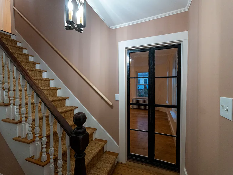 Entrance foyer with elegant glass doors into the living space and stairs up to the bathroom and bedrooms