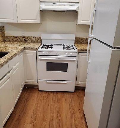 Kitchen with new granite counter tops, gas stove, and refrigerator.