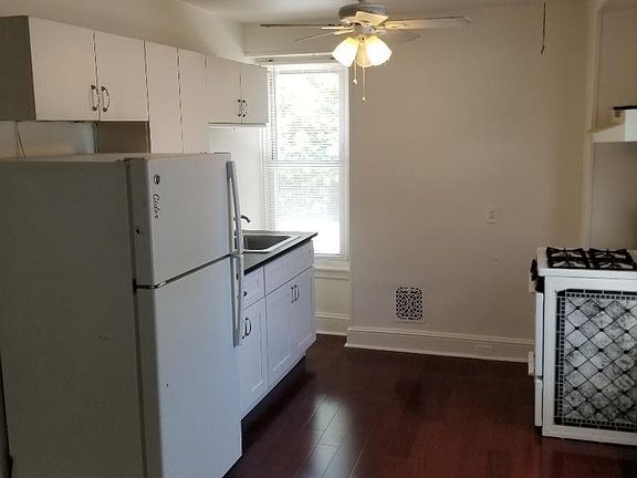 Eat-in kitchen with hardwood flooring, gas range and two-large windows.