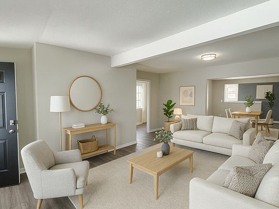 Living room with new luxury vinyl plank flooring throughout. Looking towards dining room and kitchen in background, and bedrooms to the left