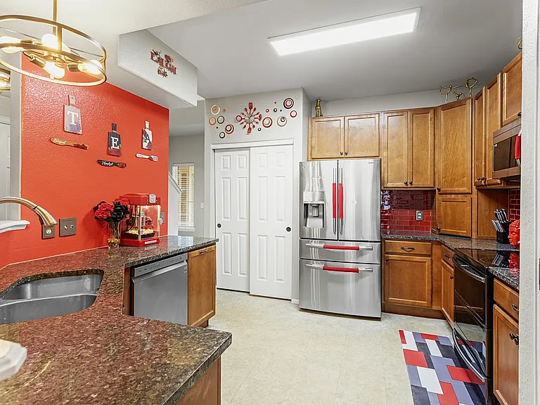 Spacious and well-equipped kitchen with modern appliances and a stylish red accent wall. Perfect for cooking up a feast or enjoying a quick meal.