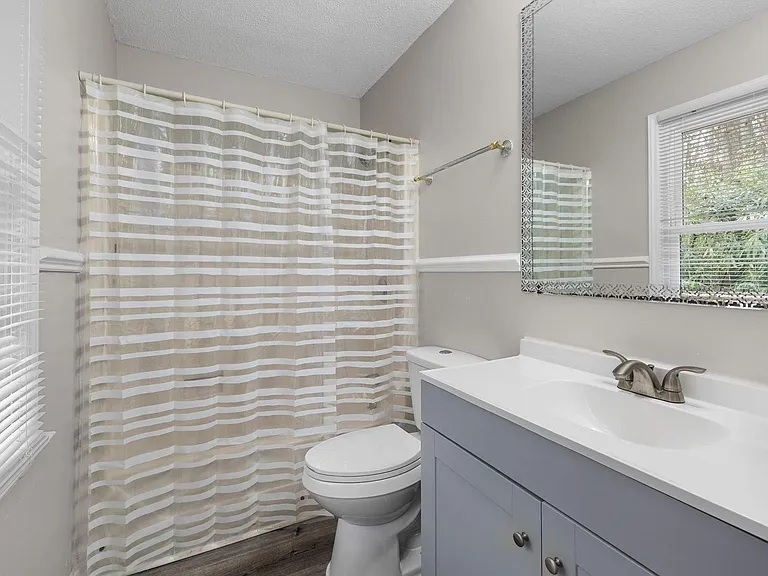Full bathroom with tub/shower combo, vanity with storage, and a window for natural light and ventilation.