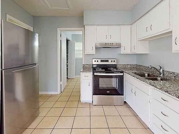 Bright modern kitchen featuring sleek stainless steel appliances, elegant granite countertops, and ample white cabinetry.