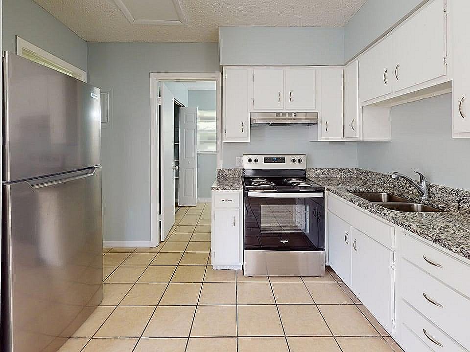 Bright modern kitchen featuring sleek stainless steel appliances, elegant granite countertops, and ample white cabinetry.