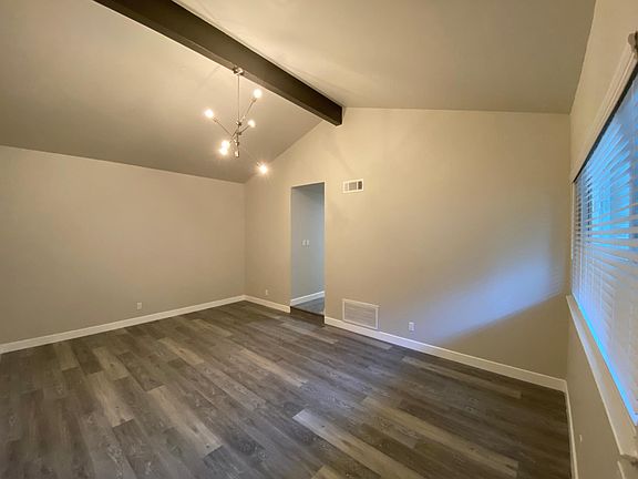 Spacious living room with vaulted ceilings, beautiful beam, and new chandelier.