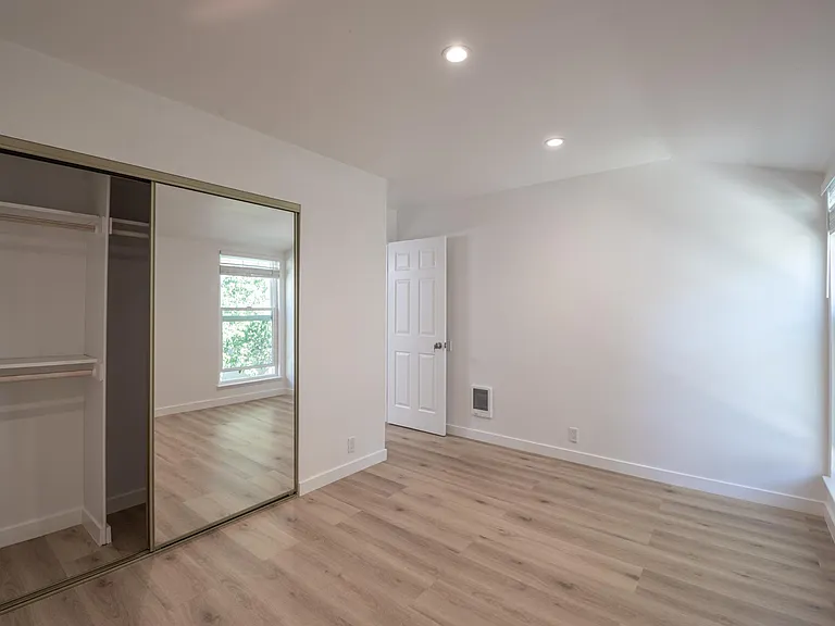 Another view of front bedroom showing the large closet with all new sliding mirrored doors, recessed dimmable lights, double pane windows and efficient electric wall heater.