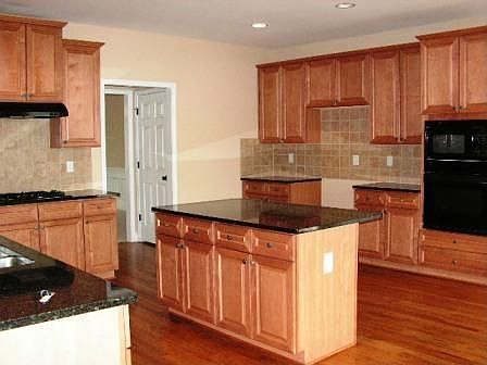 Kitchen w/ Hardwoods, Island, Tile Splashback, Granite countertops