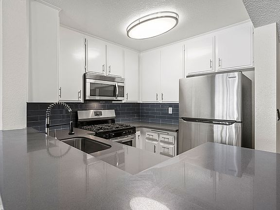 Kitchen with stainless steel oven, microwave, and fridge.