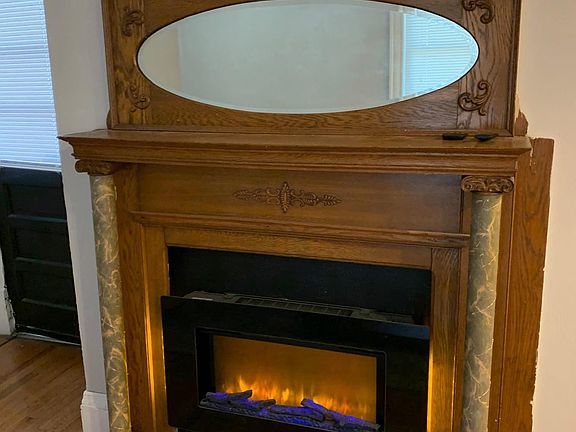 Living Room (prior to new paint) w/ Original Mirrored Fireplace Mantle w/ Electric Fireplace for Additional Heating or Ambiance.
