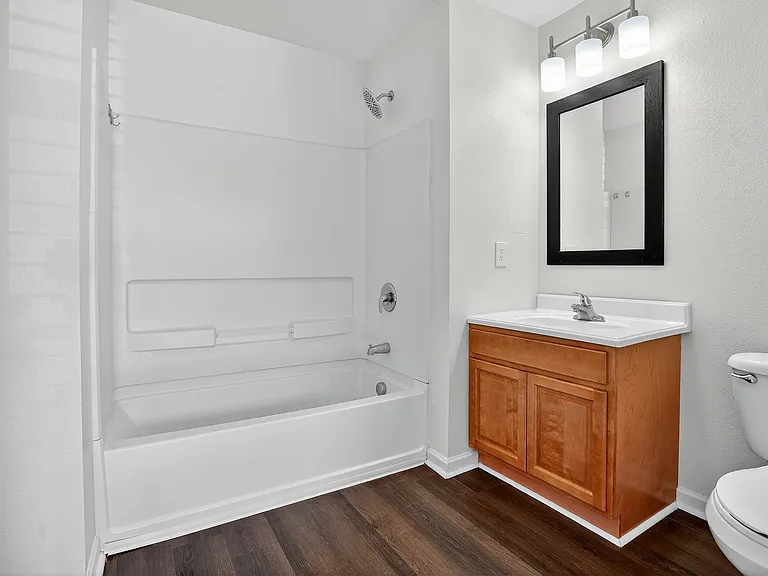Sleek bathroom with modern fixtures, inviting bathtub, elegant wooden vanity, and contemporary lighting.
