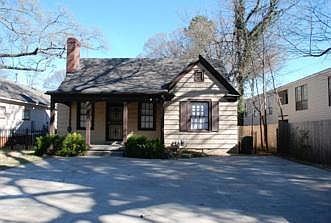 Winter view of house; paved parking in front.