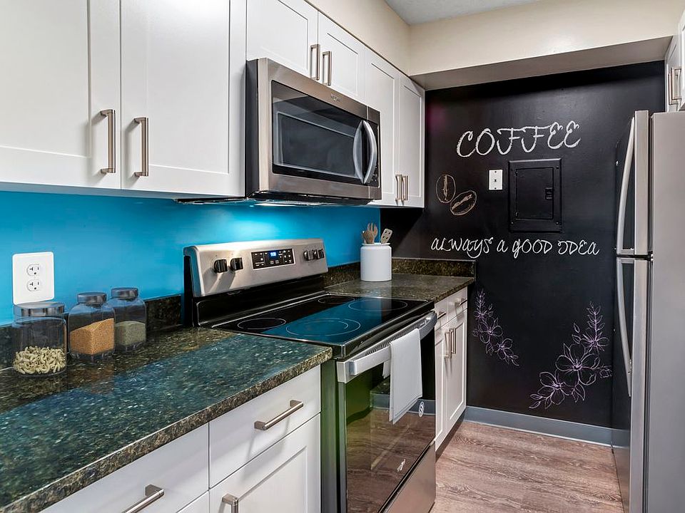 Renovated Package II kitchen with new white cabinetry, granite countertops, stainless steel appliances, painted backsplash, chalkboard accent wall, upgraded lighting and fixtures, and hard surface flooring