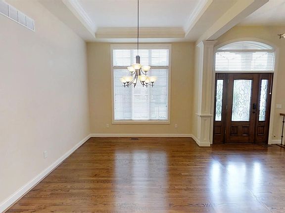 Dining room and entry hall. Side and transom windows around the front door, keyless entry system, hardwood floors, and a tray ceiling in the dining room.