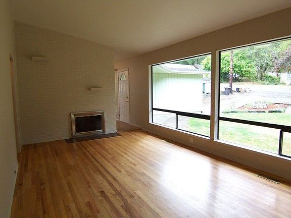 Spacious living room w/hardwoods throughout, cathedral ceilings, painted wood fireplace & wall of wi