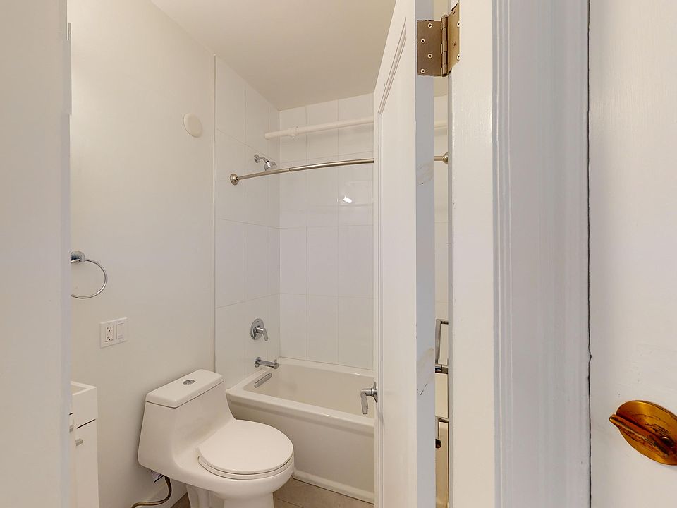 Compact bathroom with walls features a toilet next to a bathtub with shower. The open door highlights a simple, clean design.