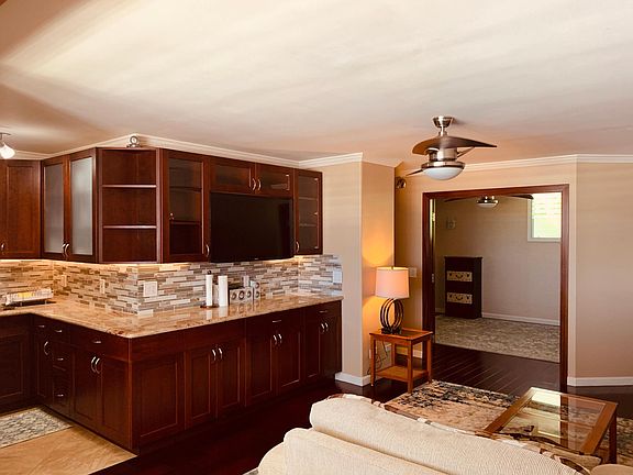 Large living area with wall mounted TV. Ceiling fans in both living and bedrooms. Crown moulding throughout.