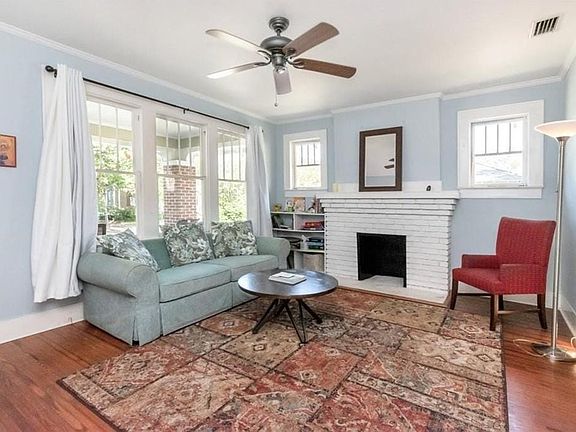 Living room with ornamental molding, dark hardwood / wood-style floors, ceiling fan, and a brick fireplace