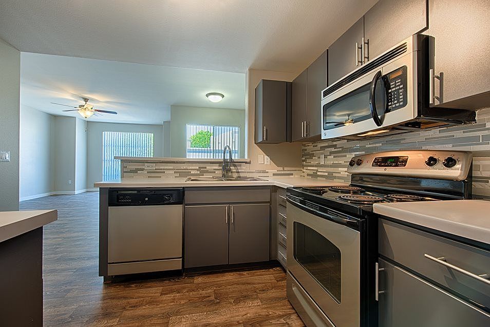 Kitchen with gray slab cabinets, stainless steel appliances, and glass mosaic backsplash.