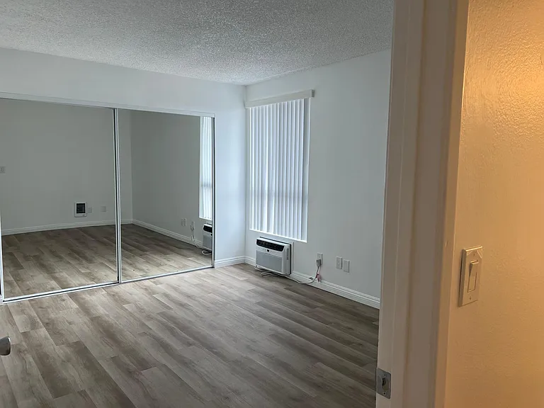 Upstairs primary bedroom with large mirrored closet doors and air conditioner. 1x1