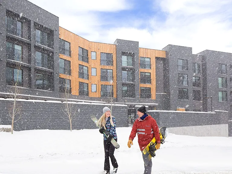 Canyon Haus snowy exterior with couple walking to the lifts.