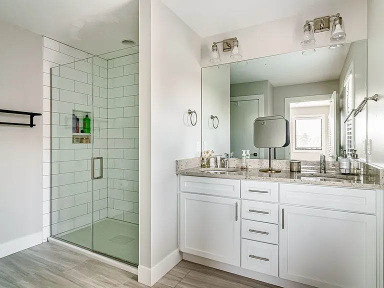Primary en suite bathroom with double vanity and walk-in tiled shower