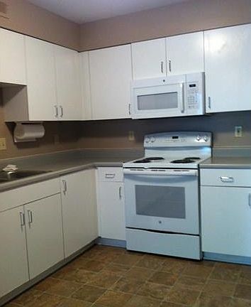 Kitchen with lots of cabinets, counter space, built in white space saver microwave, new GE stove.