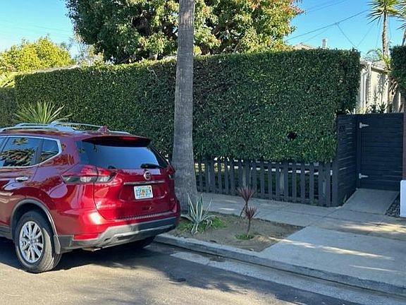 View of front sidewalk with privacy hedge at front of house and locked gate to unit.