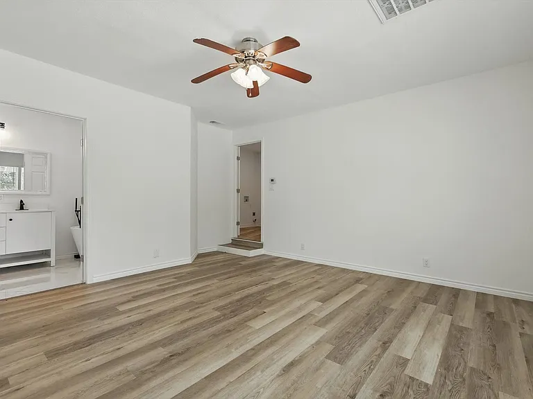 Unfurnished bedroom with light wood finished floors, baseboards, ceiling fan, and ensuite bath