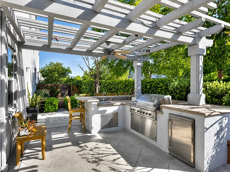 Private backyard retreat with built-in BBQ kitchen, fountains, and lush landscaping.