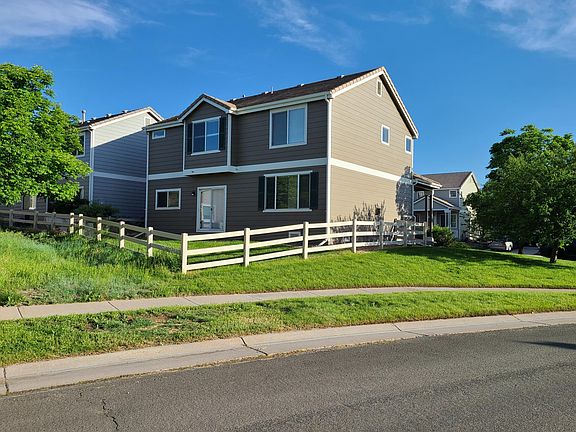 View from street of fenced yard and back/side of house