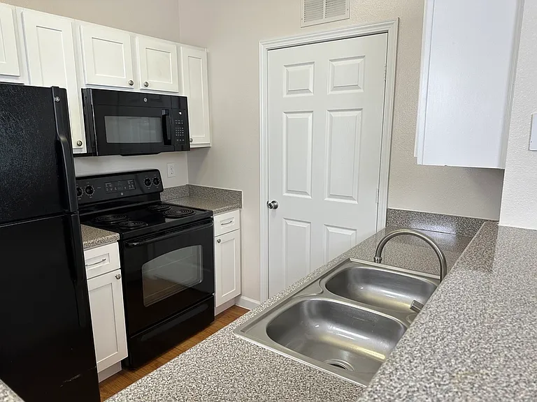 Modern kitchen with sleek countertops, dual stainless steel sink, and black appliances for a stylish touch. Modern kitchen with sleek countertops, dual stainless steel sink, and black appliances for a stylish touch.