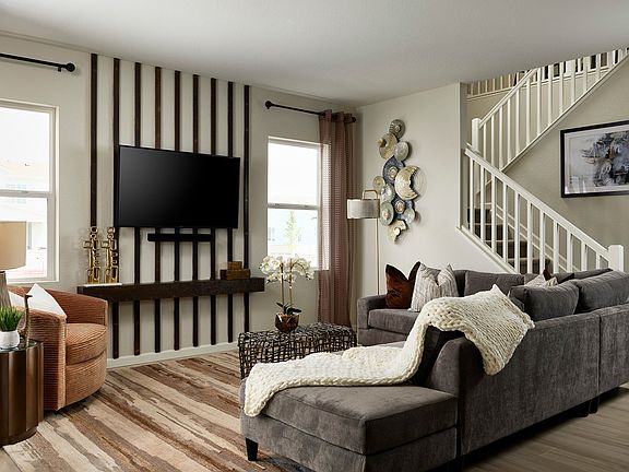 A cozy and inviting living room with a large gray sectional sofa, a TV mounted on the wall, and vari