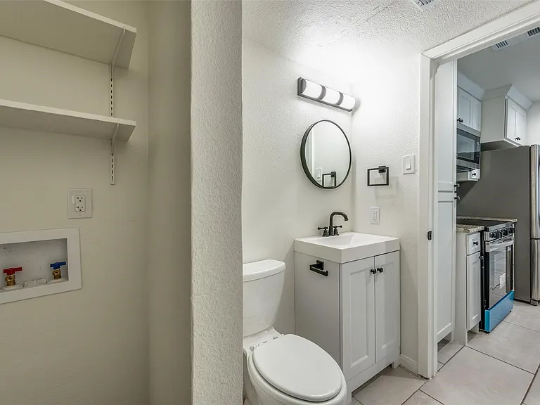Full bathroom featuring a white vanity with a rectangular sink, black faucet, and round mirror