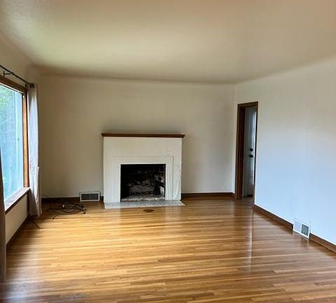 Living room with original hardwood floors and gas fireplace.