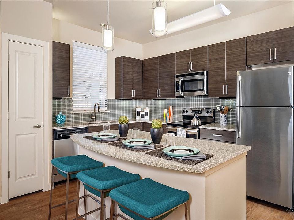 Kitchen with granite countertops, stainless steel appliances, wood-style floors, and modern lighting over island