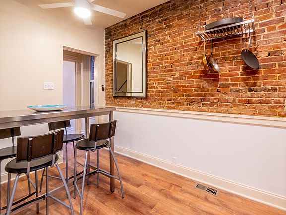 Eat in kitchen with exposed brick wall and a pot rack.