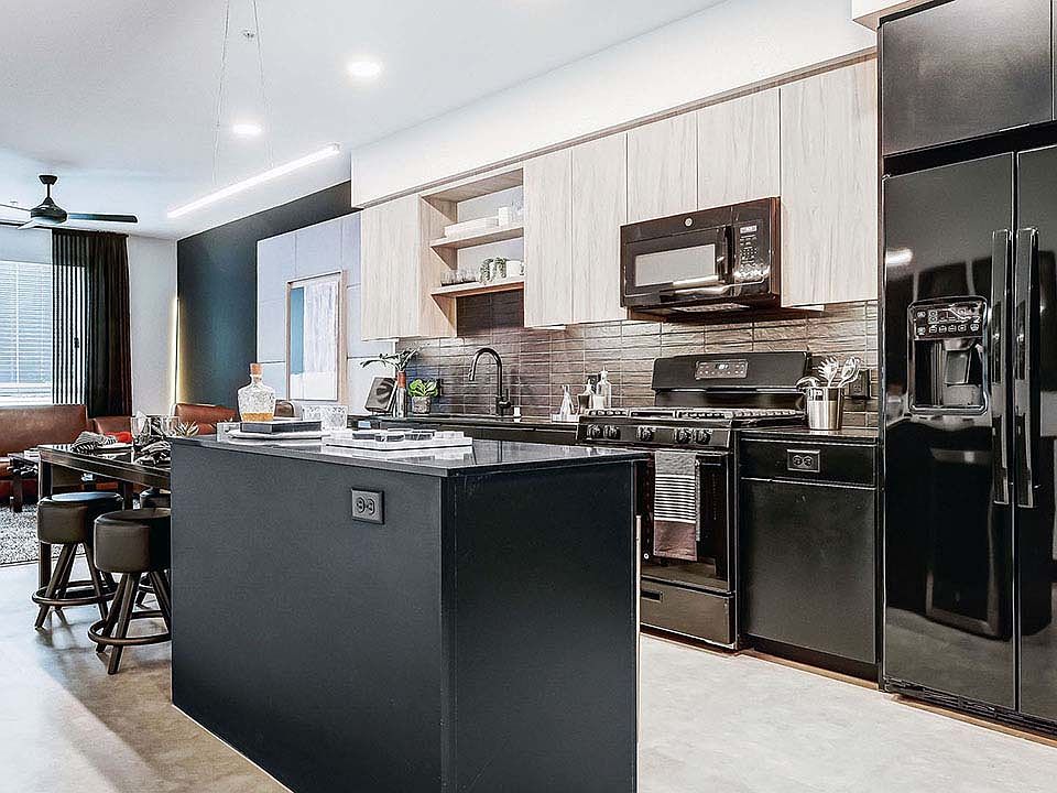 Griffis Platinum Triangle apartment kitchen with quartz countertops and black appliances.
