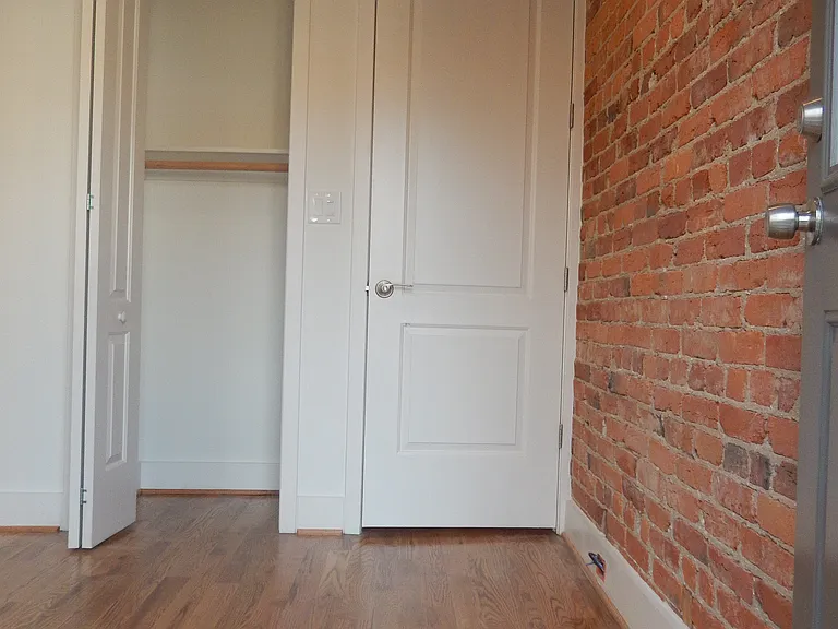 Exposed brick wall in bedroom from rear exit.