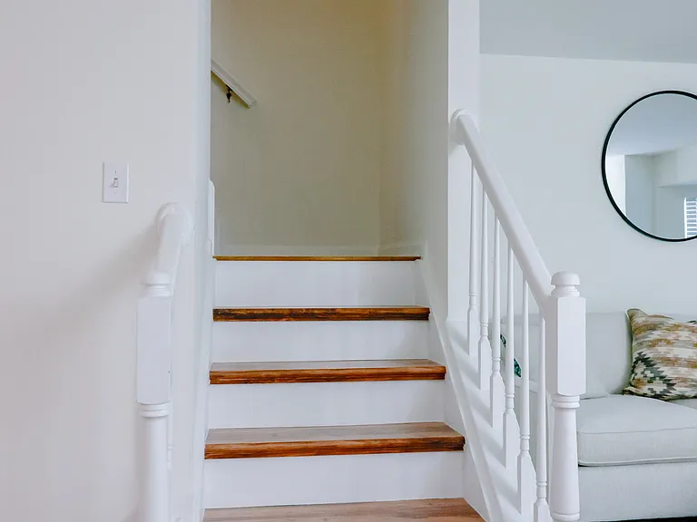 Updated staircase with hardwood treads and classic white railings, enhancing the home's bright and open layout.