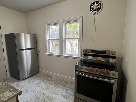 Galley kitchen with new flooring refrigerator & electric stove.