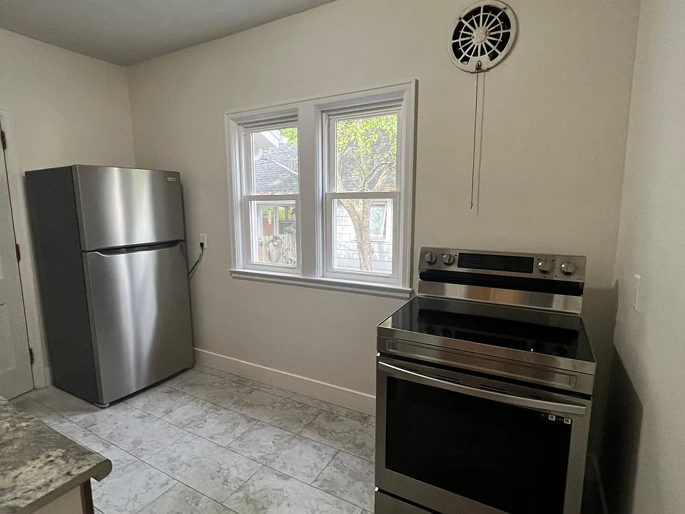 Galley kitchen with new flooring refrigerator & electric stove.