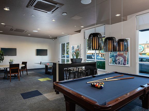 Game room with pool table, ping pong table, TV, and dining seating.