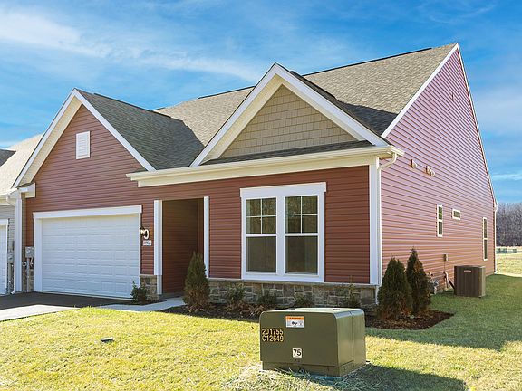 Front of home with covered entry red exterior stone watertable of a DRB Homes Finch home in the R