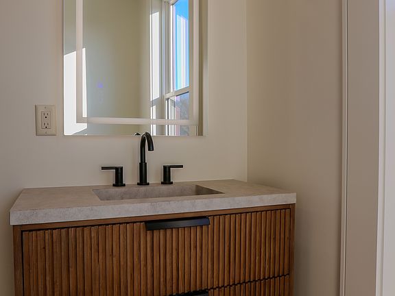 Bathroom boasts floating vanity with cement counter/sink, tile shower with sliding glass shower door and tile floors.