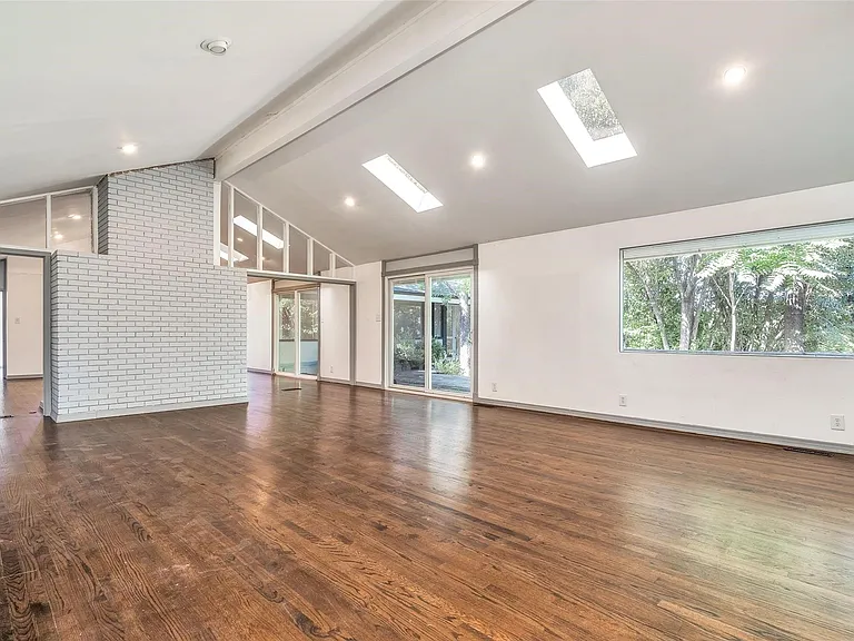 Expansive living space featuring wood-finish flooring, vaulted ceilings, and recessed lighting