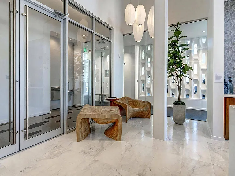 Entryway to Lounge With Wood Chairs, Pendant Lighting, and Plant Decor