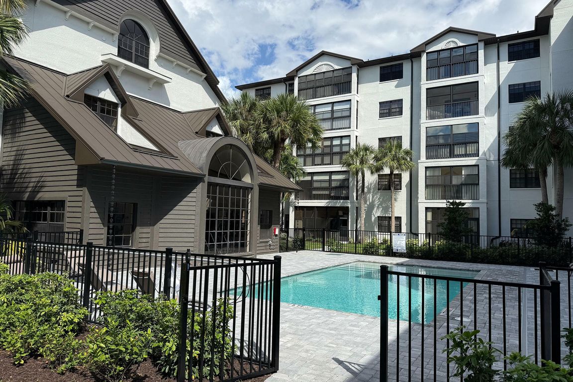 Charming apartment complex with a refreshing pool, modern architecture, and lush palm trees under a bright blue sky.