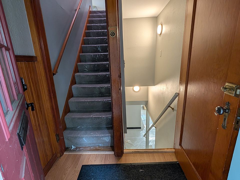 Inside entryway providing upstairs access to apartment, downstairs access to office space and laundry room plus storage room.