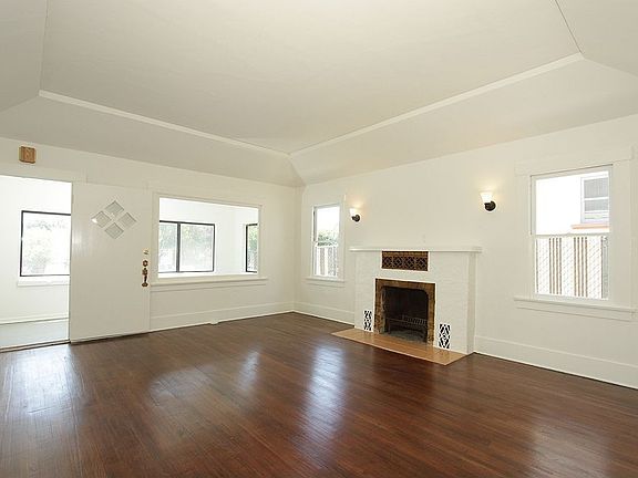 Spacious Living Room with Recessed Tray Ceiling and Wood Burning Fireplace