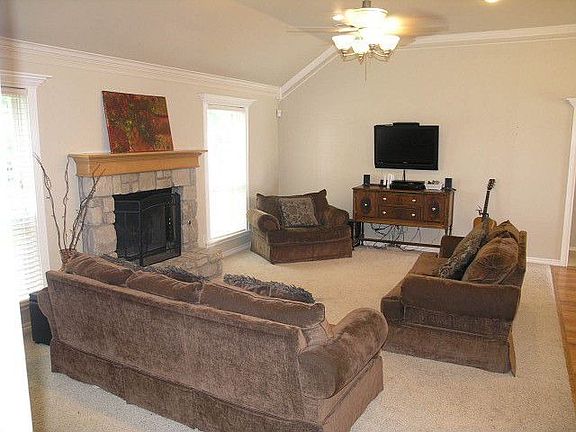 Great room withstone fireplace and ceiling fan.